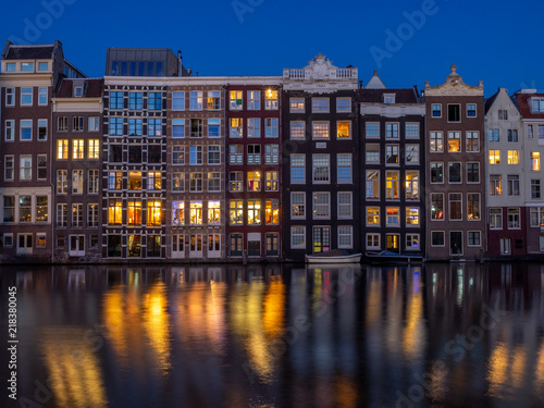 Historic buildings on the Damrak canal in the centre of beautiful Amsterdam at night.