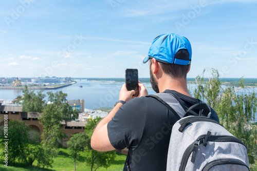 Tourist photographs on a mobile phone the confluence of the Oka and Volga rivers from the observation deck in the Nizhny Novgorod Kremlin