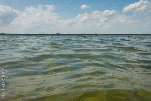Lake on a sunny day with ripples on the surface of the water  blue sky and white clouds. Selective focus