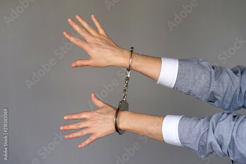 Arrested woman handcuffed hands. Prisoner or arrested terrorist, close-up of hands in handcuffs isolated on gray background. Criminal female hands locked in handcuffs. Close-up view
