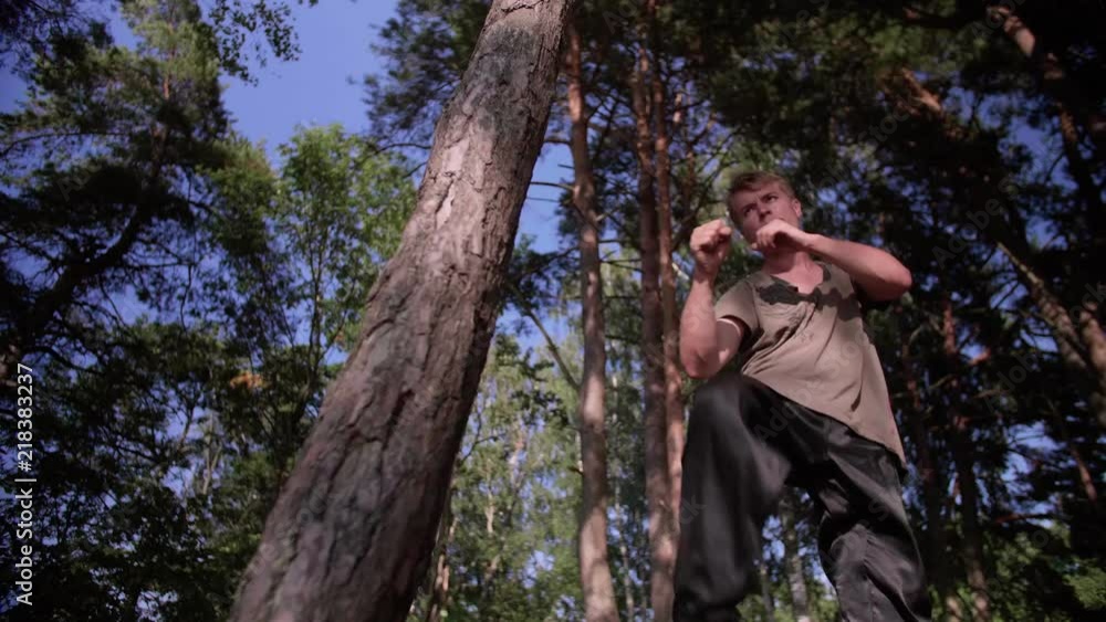 Caucasian man practicing traditional martial arts kicks on a tree in a forest, 50 fps slow motion converted to 25 fps Caucasian man practicing traditional martial arts kicks on a tree in a forest, 50 fps slow motion converted to 25 fps