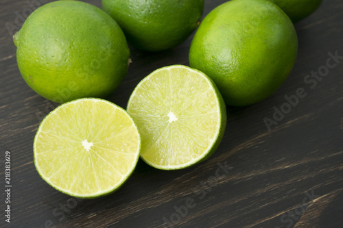 Sliced and whole limes on a wooden cutting board
