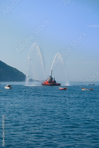 Two jets of sea water sprayed by a fire engine of a firefighters red boat
