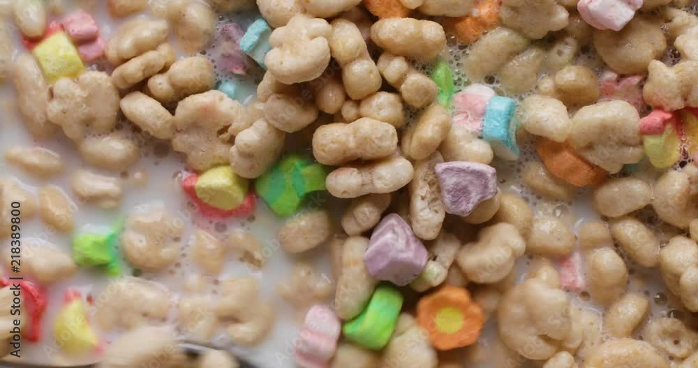 Top close view of a using a spoon to stir generic crunchy breakfast cereal with milk then taking a spoonful at the end. Top close view of a using a spoon to stir generic crunchy breakfast cereal with milk then taking a spoonful at the end.