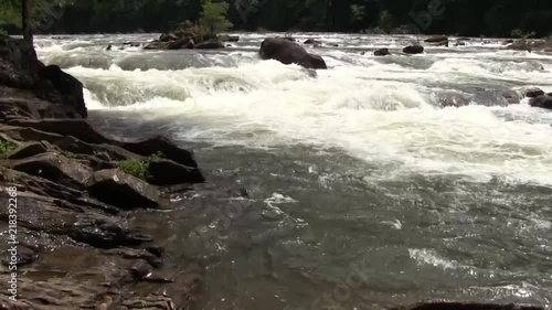 pull pan from tight shot of wet rock to wide shot of rushing river