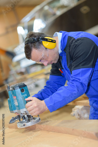 Foto worker sanding wood for luxury yachts in boatyard