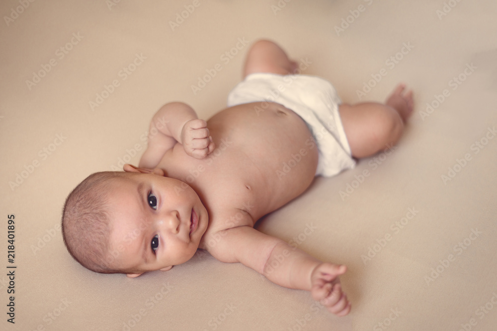 cute newborn baby girl lying on simple isolated beige background cute newborn baby girl lying on simple isolated beige background