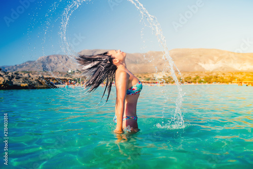 beautiful woman splashing water with her hair. Portrait of summer lifestyle and beach activities