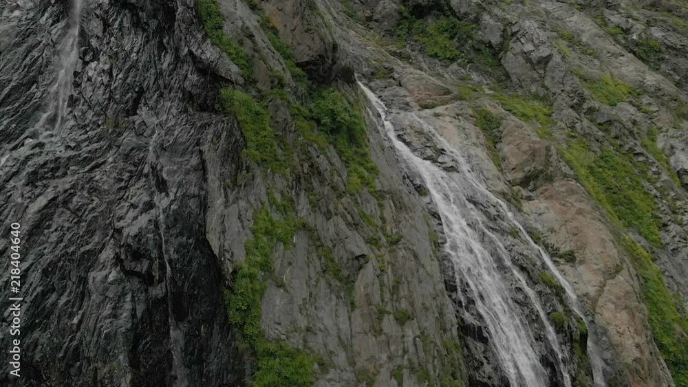 Tracking and top shot Air shot from a stream of water splashing waterfall on a rock wall in the Caucasus Mountains. Around the jet of the waterfall Tracking and top shot Air shot from a stream of water splashing waterfall on a rock wall in the Caucasus Mountains. Around the jet of the waterfall
