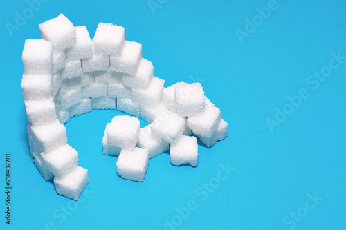 Cubes of sugar on a blue background. The castle is built of sugar cubes. Sugar destroys