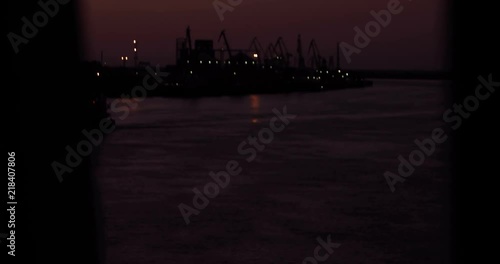 Seaport in the night time with boats go left then right, shot through window with curtains