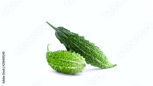 Two whole green bitter melons are rotating on the turntable isolated on the white background. Close-up. Macro. photo