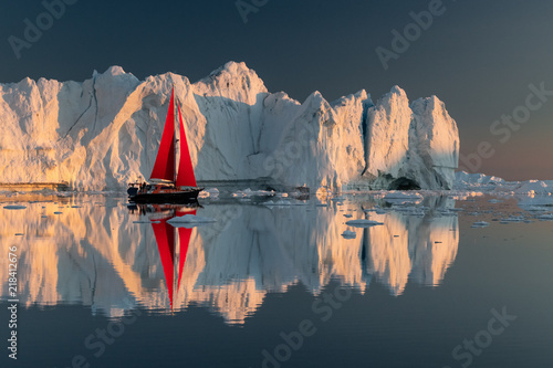 Greenland midnight Sunset iceberg perfect reflection panorama with red sail ship 