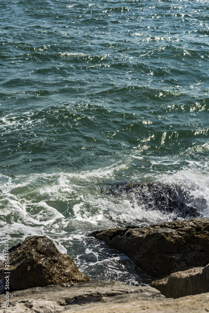 Small ocean sea waves on stone beach. Background wallpaper picture with roaring waves.