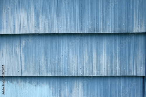 blue painted asbestos shingles which have weathered to look like corrugated denim