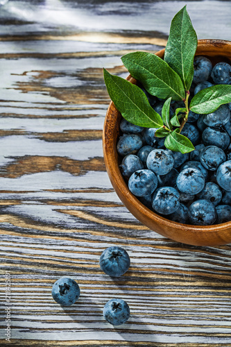 Juicy huckleberries in round wooden bowl