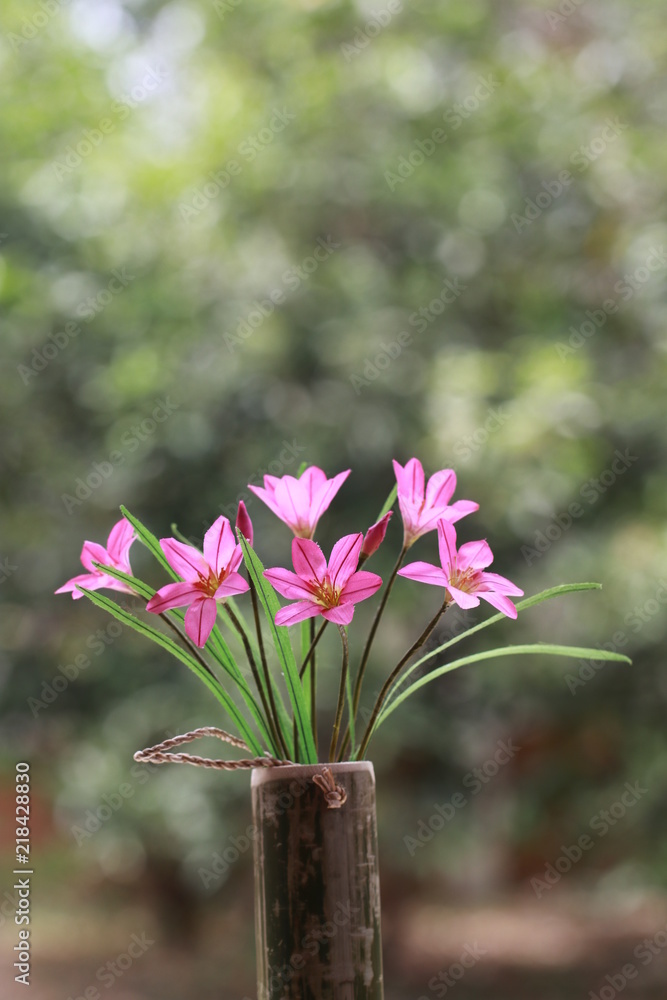 Transparent pink fabric flowers in bamboo tube and white bokeh on green background