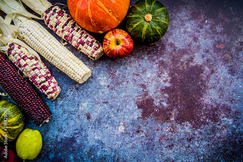 corn cobs and vegetables on dark background with copy space top view