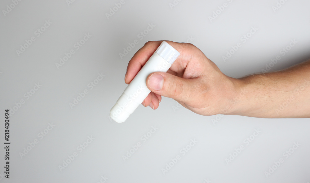 Glue stick in hand on a light background Glue stick in hand on a light background