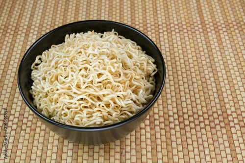 Instant noodles in a black bowl on Japanese mat
