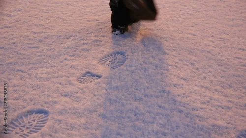 girl walking through the snow in winter boots, leaving behind traces.