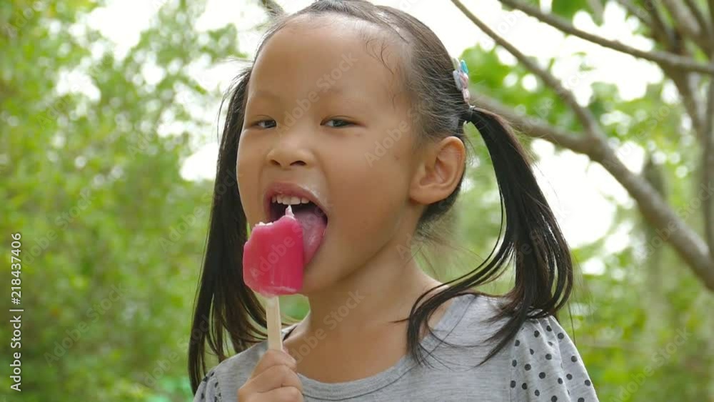 Little asian girl eating ice cream in park,slow motion.
Little asian girl eating ice cream in park,slow motion.