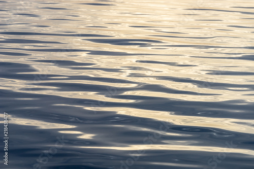 Sea water surface with reflection of the sun and small wave showing Gold metallic color looks.