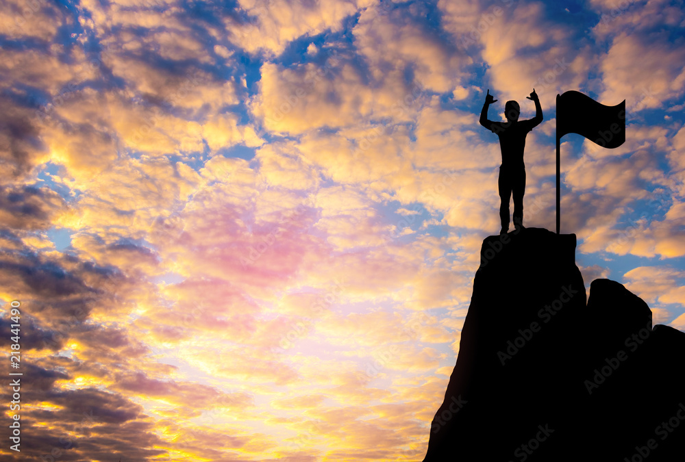 A man and  flag  Silhouette  photo.A man show hand and standing on cliff. A man happy and good feel  for nature. lifestyle , freedom  , He is see sun set. Photo concept  achievement and Silhouette.