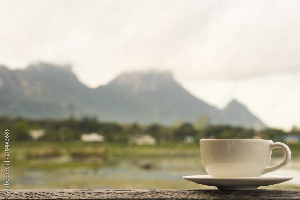 white cup on wooden table with lake view