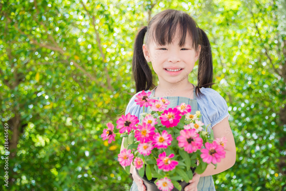 Little asian girl holding flower pot and smiles in garden Little asian girl holding flower pot and smiles in garden