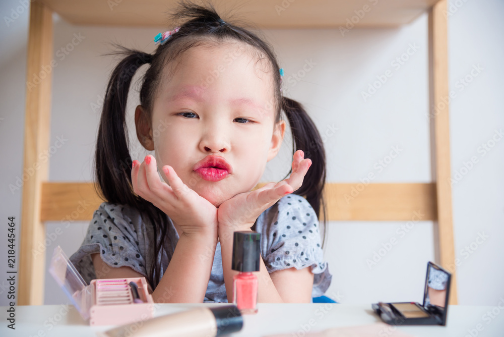 Little asian girl having fun while makeup her face with cosmetic by herself Little asian girl having fun while makeup her face with cosmetic by herself