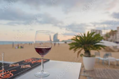 A glass of red wine on a bar overlooking the beach in Barcelona  Spain at sunset. Concept of a relaxing  blissful vacation.