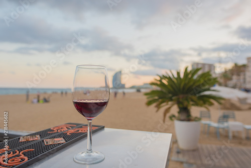 Photography A glass of red wine on a bar overlooking the beach in Barcelona, Spain at sunset