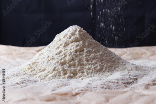 Handful of flour with flaky flour on a dark background.