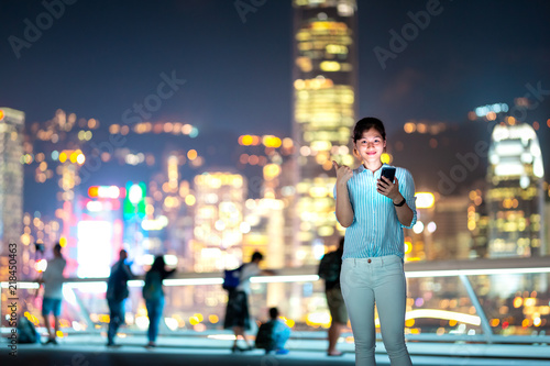 Photography Woman using smartphone at night with Victoria Horbor in background