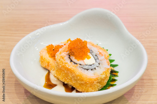 Bowl of Crispy Deep Fried Roll Sushi topped with small fish eggs. It is a new modern Japanese meal and delicacy.