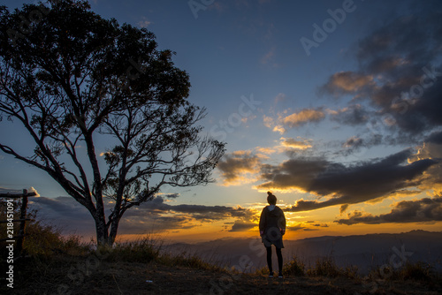 Silhouette of the Young woman looking at sunset on top mountain