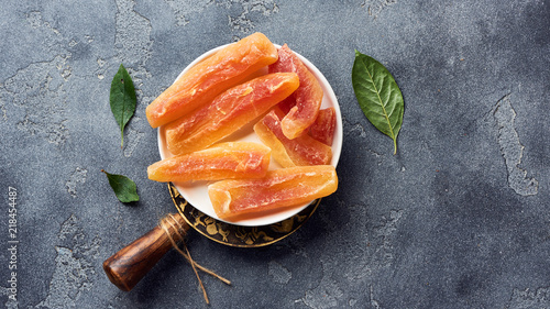 Dried sweet papaya sticks. Candied fruits on gray background. Top view. photo