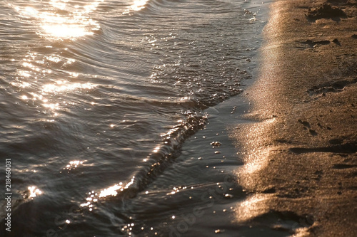 Waves on the sandy river Bank during sunset.