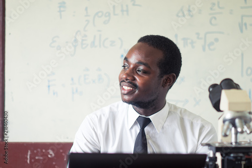 Obraz na płótnie African man science teacher smiling in the classroom with microscope