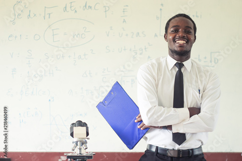 Bild auf Leinwand Africanman science teacher smiling in the classroom with microscope