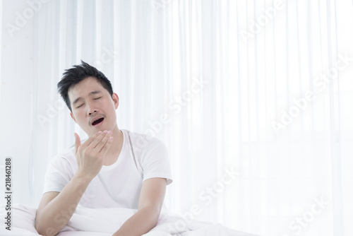 Free Download Asian man has wake up with lazying on bed in the morning. - GFXLoad
