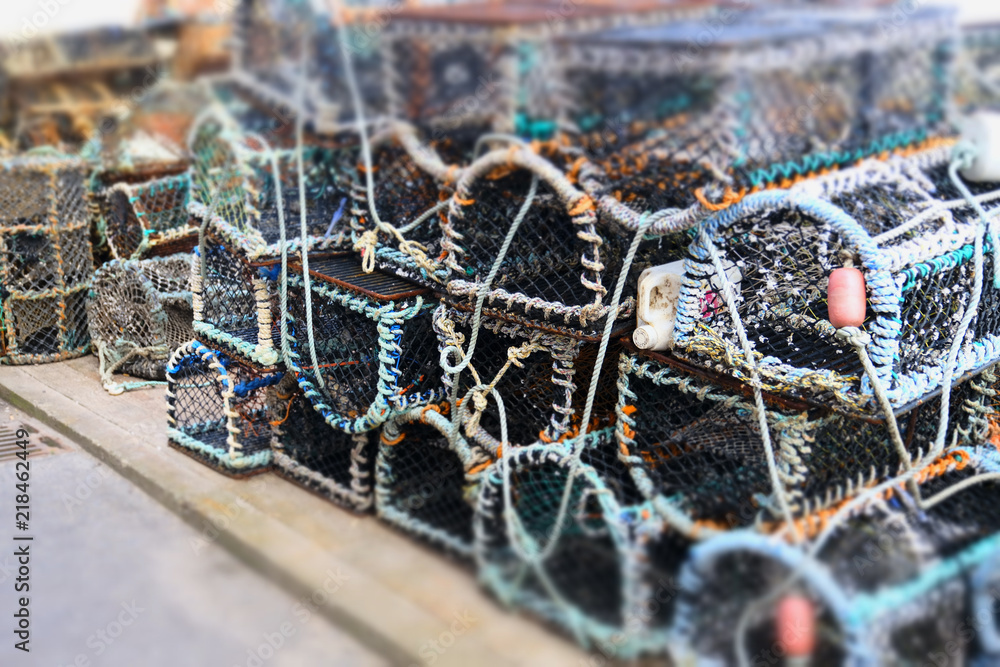 Stacked lobster fishing pots netted boxes at harbour wall