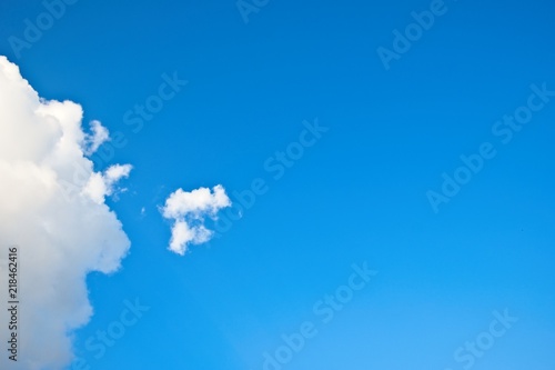 Due nuvole bianche, una grande ed una piccola, alla sinistra della foto  su cielo azzurro.  Spazio copy sulla destra