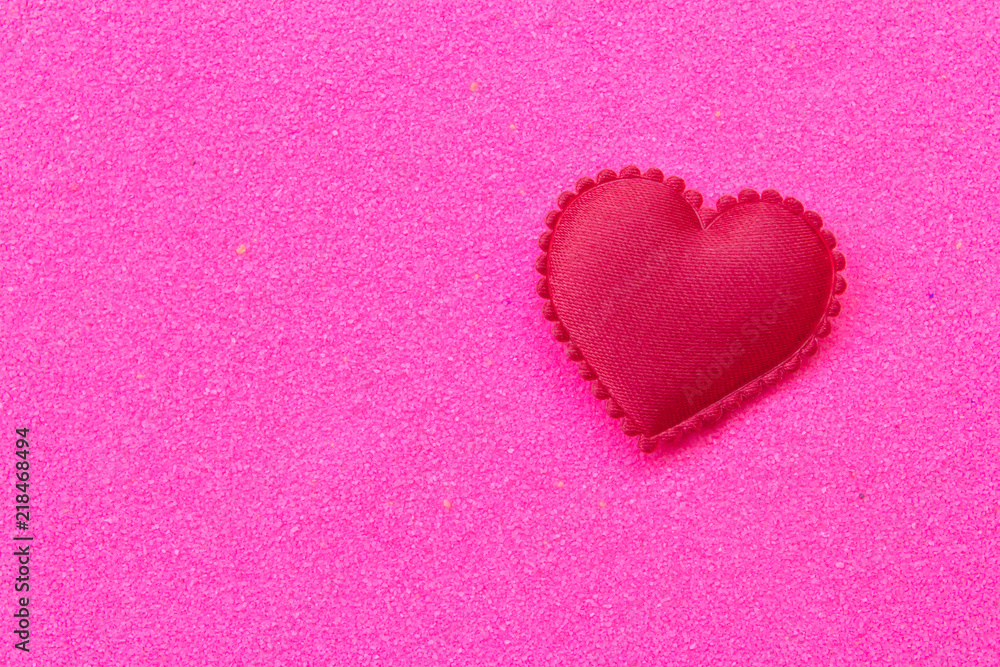 Red heart on pink sand