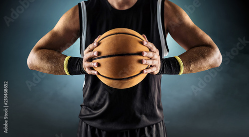 Basketball ball in a male hands, player in black with orange sport