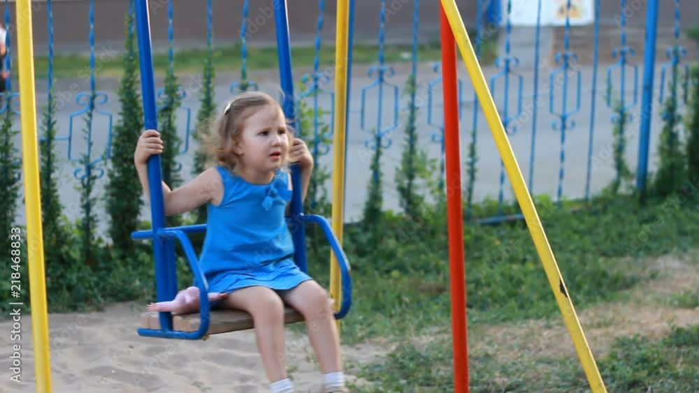 Sad child girl swings on the playground Sad child girl swings on the playground