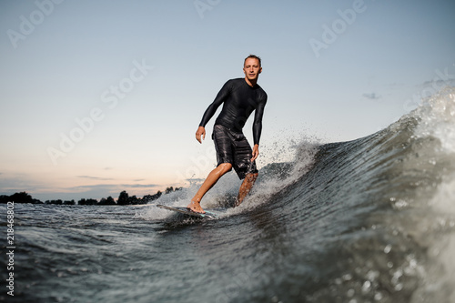 Young man riding on a wake board at the evening