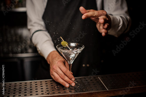 Bartender making a fresh and strong summer martini cocktail with olive and salt photo