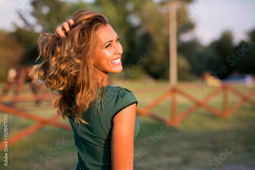 Beautiful young woman outside smiling at the sun